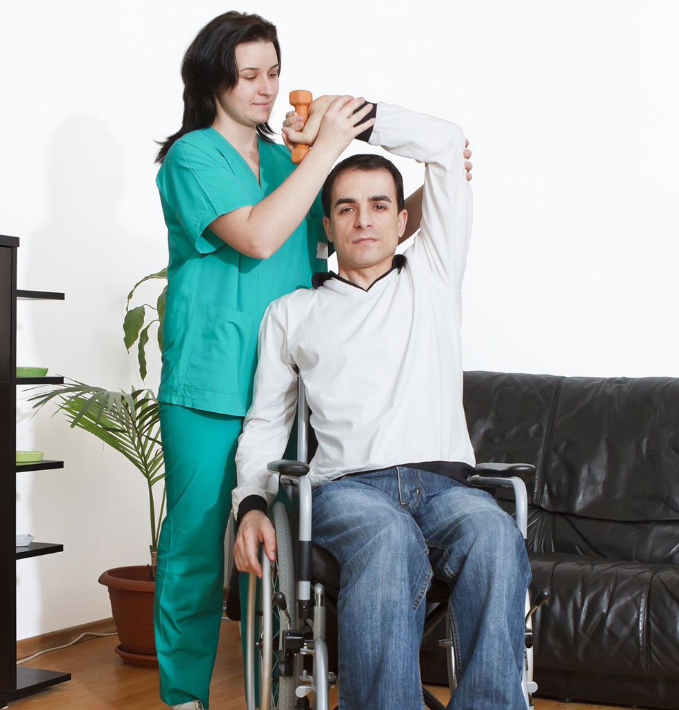 Man in wheelchair having phisiotherapy with a nurse at home